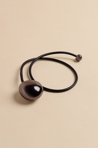 Handmade Charcoal Ceramic Bead Necklace featuring a large, smooth, dark grey bead and a smaller matching bead at the end of a black leather cord.