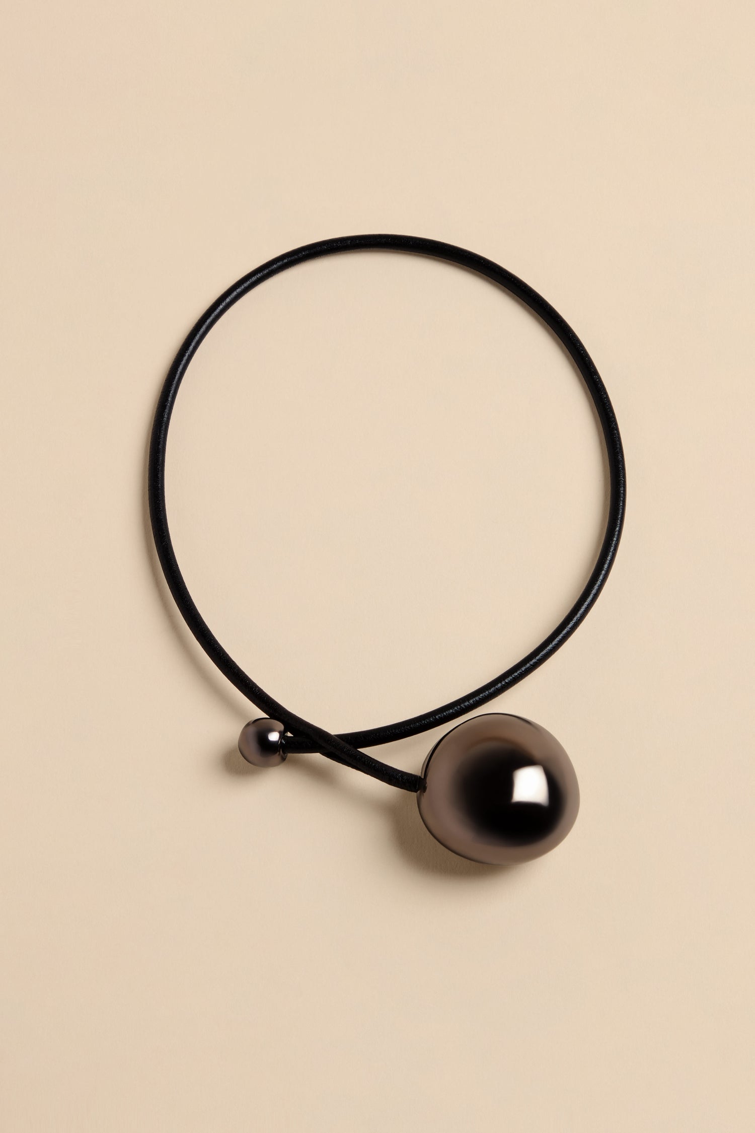 Handmade Charcoal Ceramic Bead Necklace featuring a thin black cord with a small dark bead and a single large, polished charcoal-colored bead.