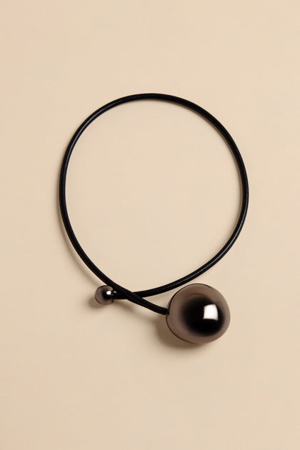 Handmade Charcoal Ceramic Bead Necklace featuring a thin black cord with a small dark bead and a single large, polished charcoal-colored bead.