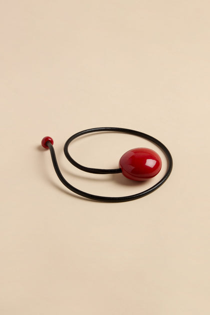 Handmade Deep Red Ceramic Bead Necklace featuring a black leather cord, a large smooth deep red ceramic bead, and a small matching bead at the end.