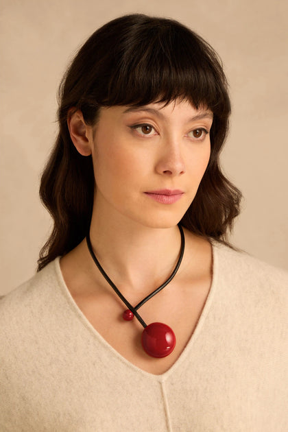 Handmade Deep Red Ceramic Bead Necklace featuring a large, glossy deep red bead and a smaller matching bead on a black leather cord.