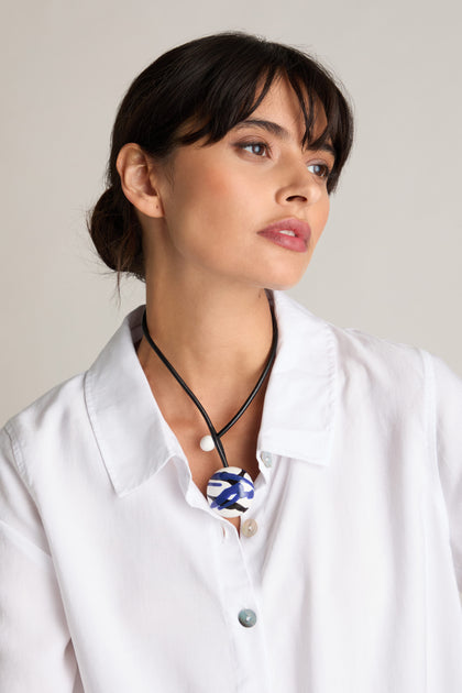 Against a neutral background, a person in a white shirt gazes to the side, showcasing the Handmade Ceramic Painted Bead Necklace that embodies contemporary design through traditional craftsmanship.