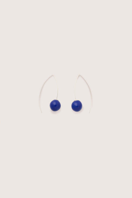 The Handmade Ceramic Bead Earrings are a pair of minimalist silver wire earrings featuring blue oval beads, showcasing artisanal craftsmanship. Fashioned from 925 sterling silver, these handmade ceramic bead earrings bring a touch of elegance to any ensemble.