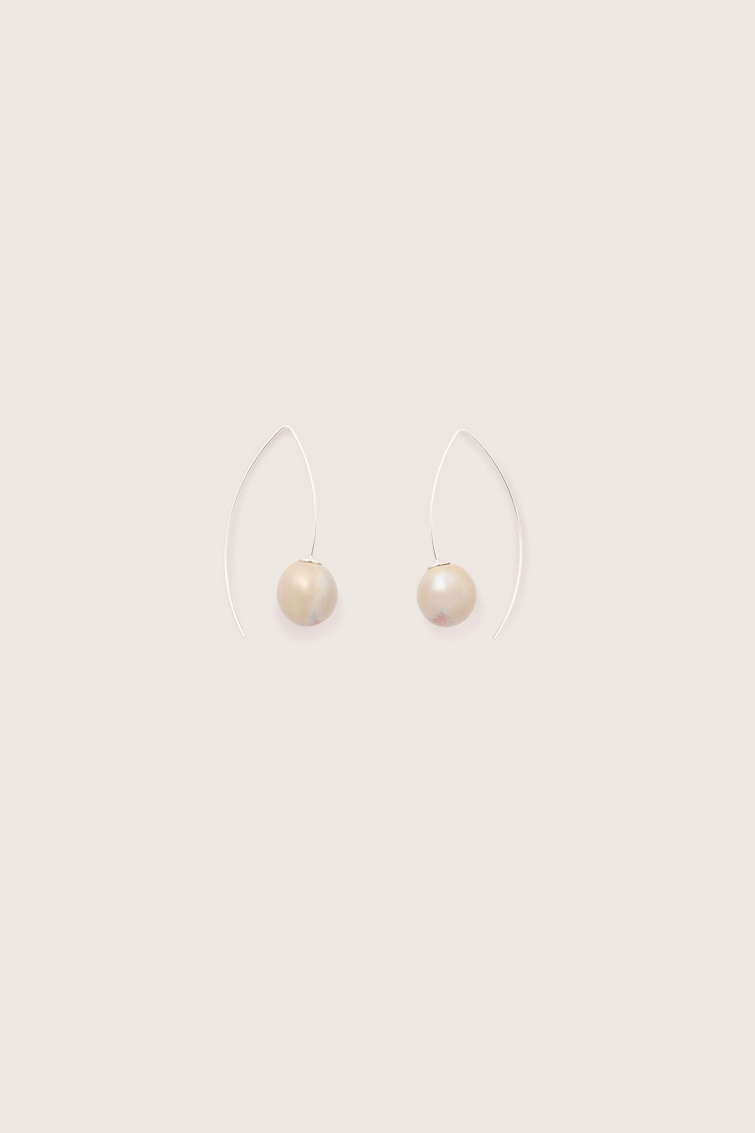 A pair of Handmade Ceramic Bead Earrings featuring white beads suspended on thin, curved 925 sterling silver wires against a beige background, showcasing artisanal craftsmanship.