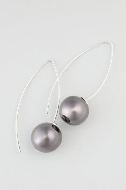 Charcoal Handmade Ceramic Bead Earrings feature round dark gray beads on curved silver hooks, evoking artisan elegance and displayed beautifully against a light background.