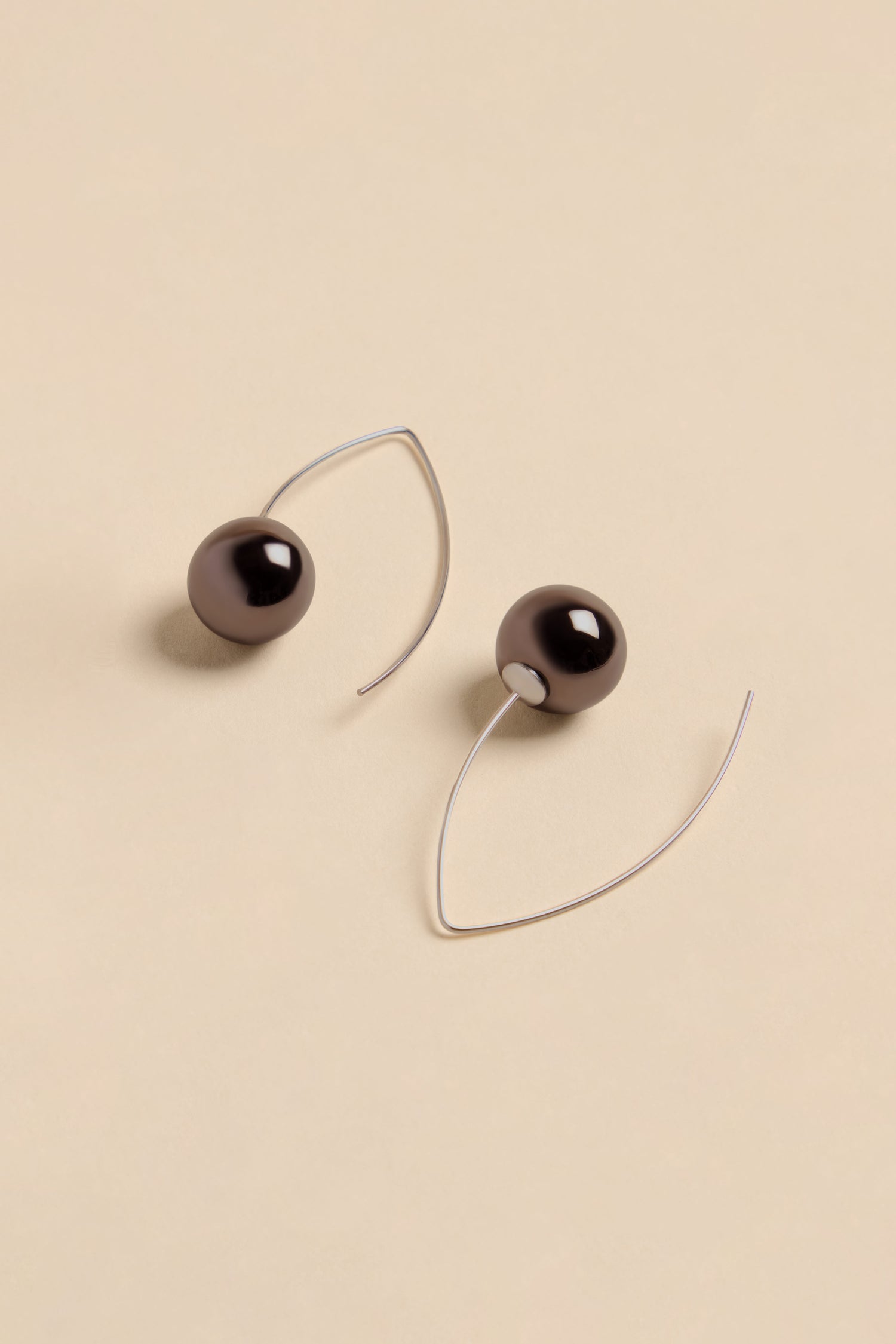 Handmade Charcoal Ceramic Bead Earrings featuring dark, spherical ceramic beads on curved silver-toned wires.