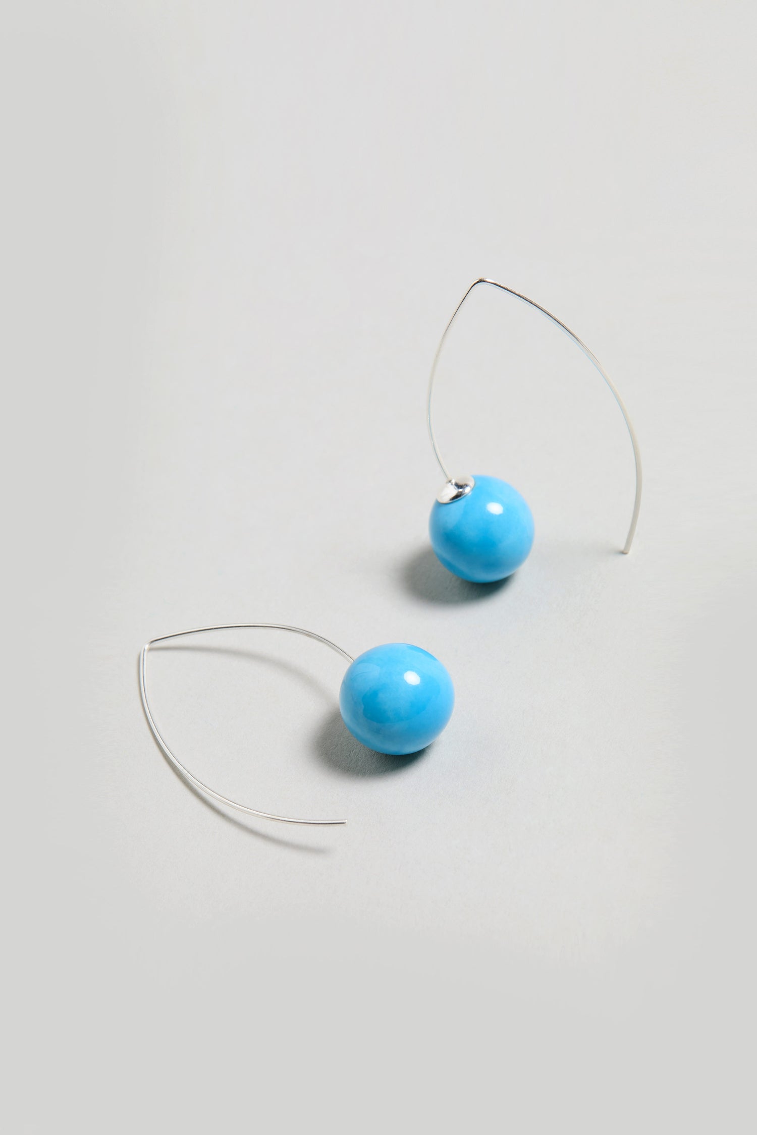 Handmade Ceramic Bead Earrings with turquoise round beads and silver hooks, displayed on a light grey background.