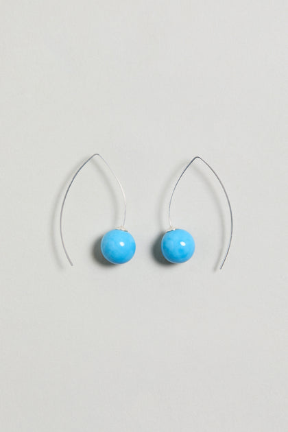 Handmade Ceramic Bead Earrings with silver hooks feature round, bright turquoise ceramic beads and are displayed on a light gray background. These earrings add a vibrant touch to any outfit.