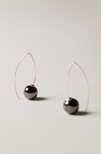 Handmade Ceramic Graphic Metal Earrings with minimalist metallic finish, featuring thin silver wire loops and dark spherical beads at the base, displayed on a light background.