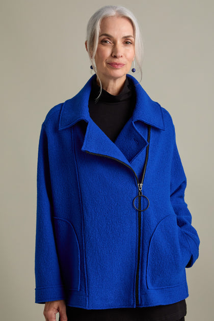 A person with gray hair is wearing a royal blue Boiled Wool Zip Boxy Jacket, which has an oversized fit, along with a black turtleneck underneath. They are posing against a neutral background.