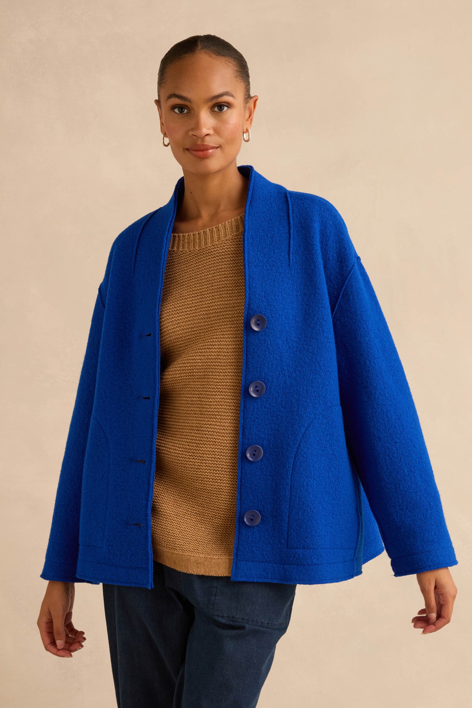 A person wearing a Cobalt Boiled Wool Cocoon Jacket in cobalt blue, button-front, boiled wool over a tan sweater.