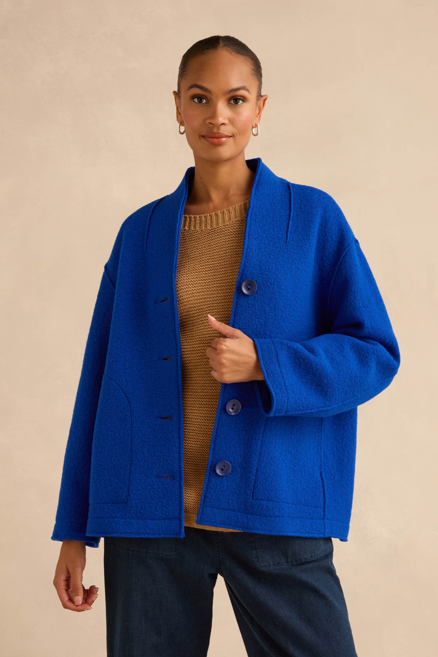 A woman wearing a Cobalt Boiled Wool Cocoon Jacket in vibrant cobalt blue over a brown knit sweater.