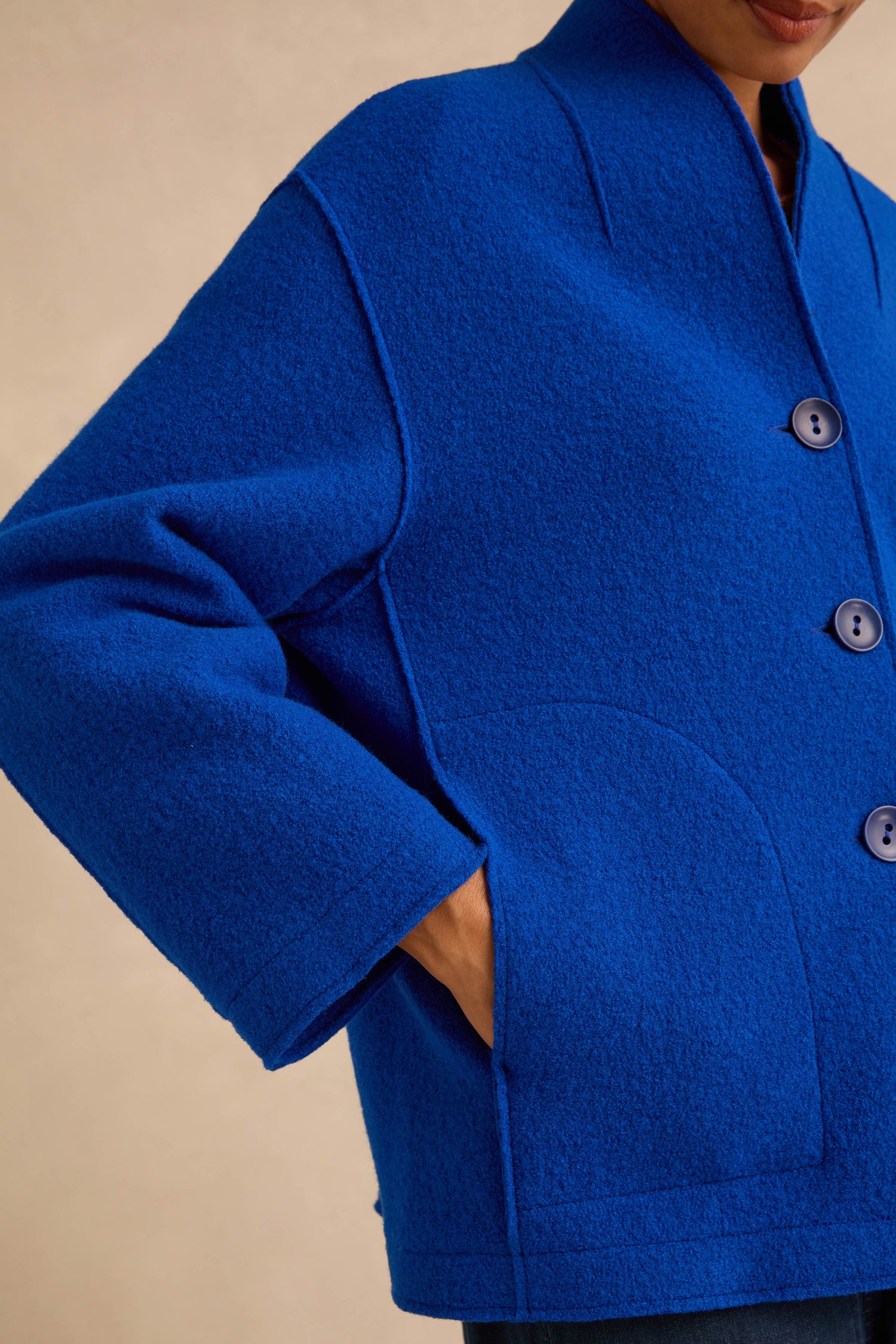 A person wearing a cobalt blue Cobalt Boiled Wool Cocoon Jacket with patch pockets and a stand collar.