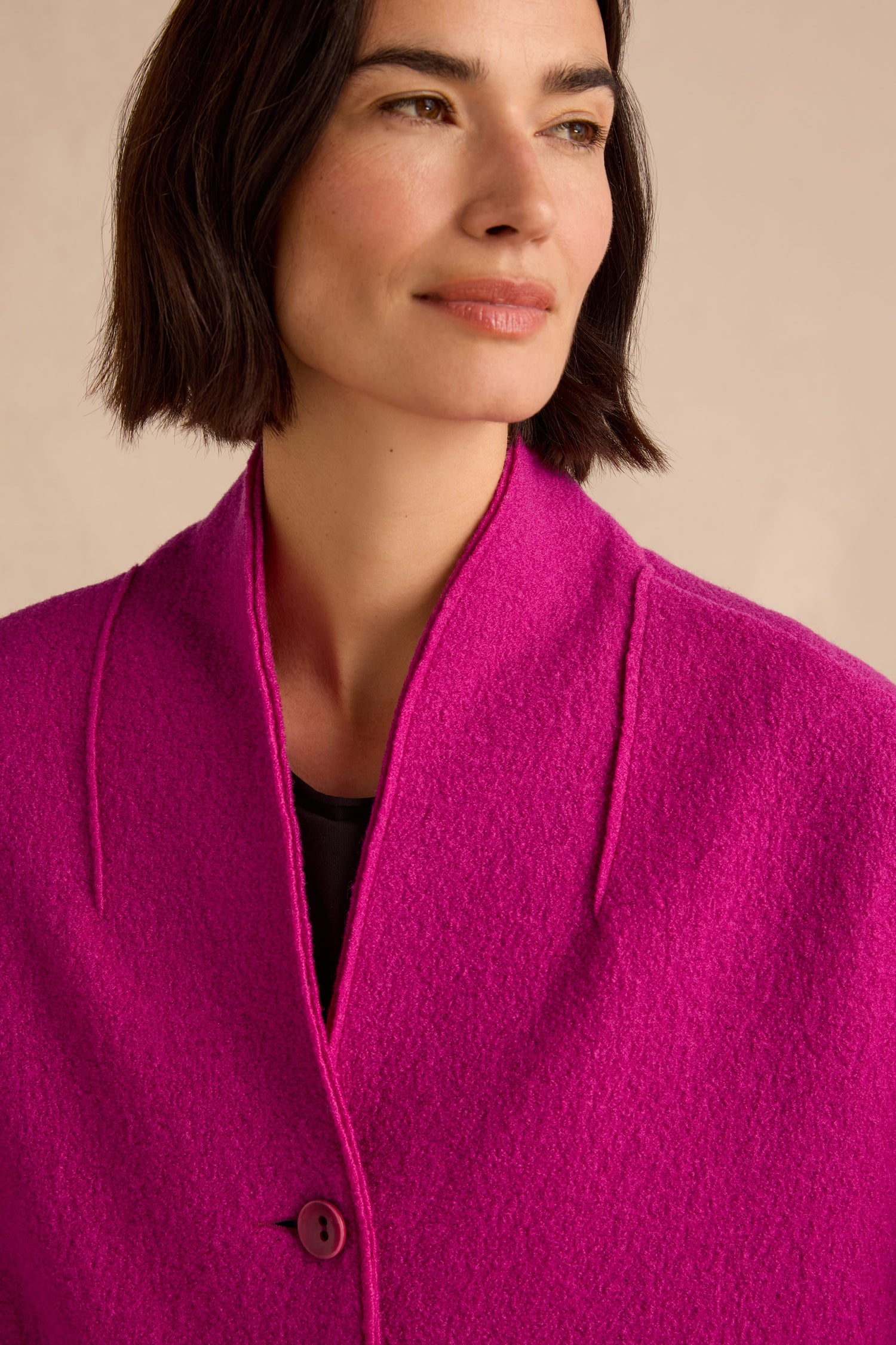 A woman with short dark hair, looking slightly to the side against a neutral background, wears the Magenta Boiled Wool Cocoon Jacket featuring a bold hue, cocoon silhouette, and single button closure.