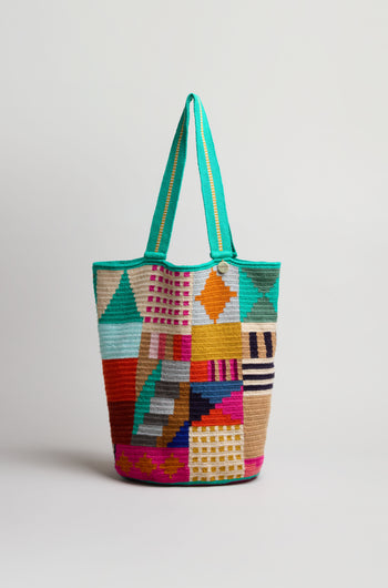 The Hand Crocheted Cala Tote Bag features a vibrant geometric design in multiple colors with a green handle, shown against a plain white background.