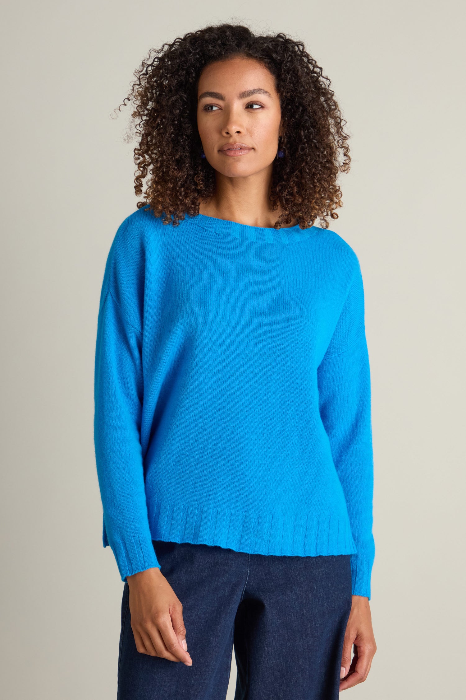 A person with curly hair wears a Cashmere Blend Crop Jumper in bright blue and dark pants, standing against a plain background.