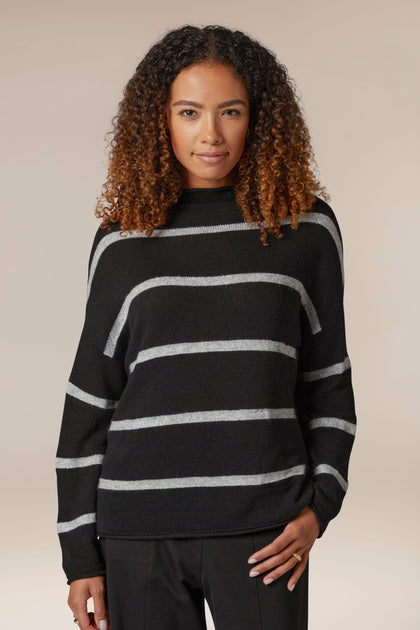 A woman wearing a Plaited Stripe Sweater in black and grey, perfect for layering knit.