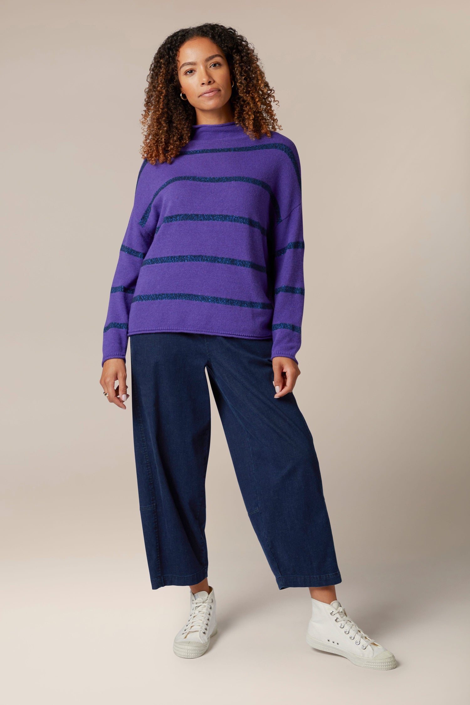 A woman wearing a Plaited Stripe Sweater with a metallic sheen.