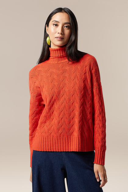 A woman wearing a high-quality Cable Knit Jumper sweater.