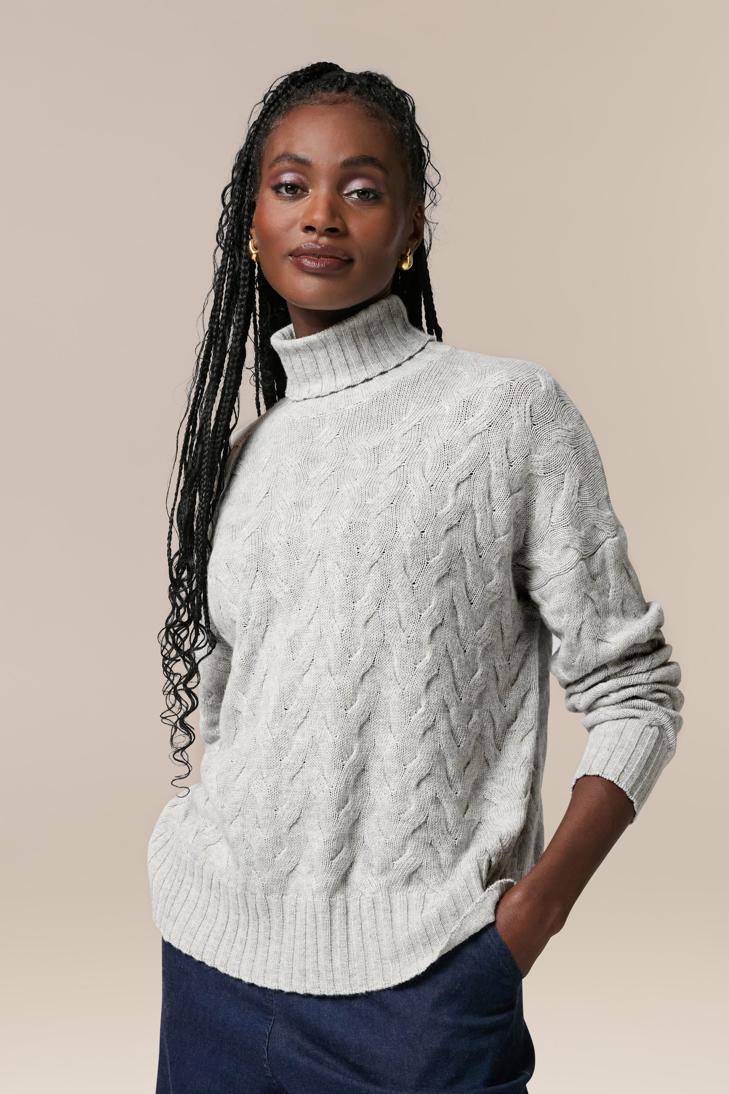A woman wearing a high-quality, grey Cable Knit Jumper turtle neck sweater.