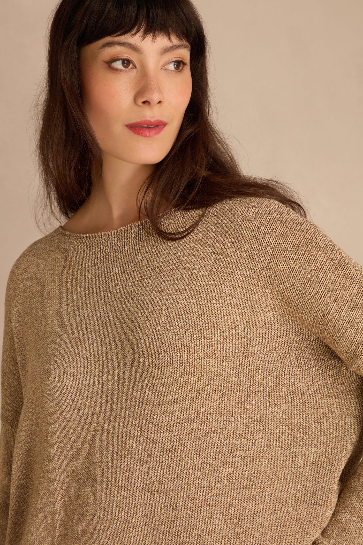 Woman with long brown hair wears the Champagne Boxy Sparkle Knit Jumper, looking to the side against a neutral background.