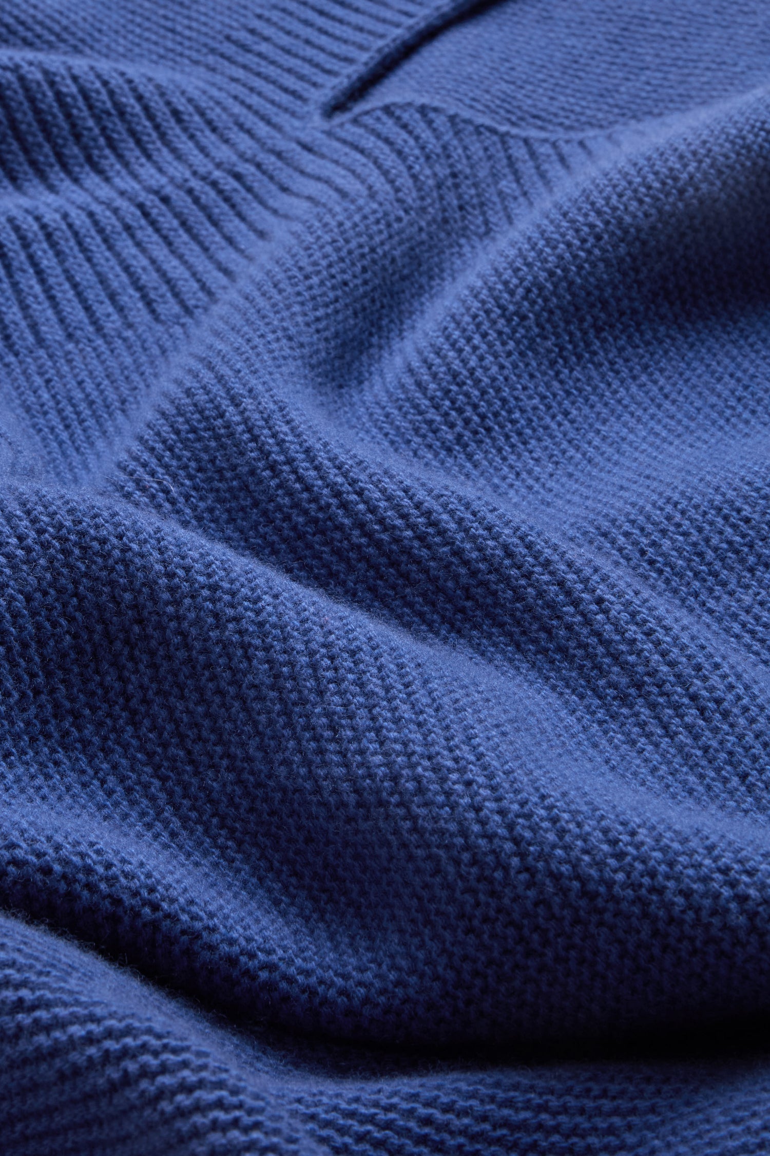 Close-up of the Royal Blue Merino Ribbed Turtle Neck Jumper, showcasing its textured blue knit with visible ribbed ridges and gentle folds.