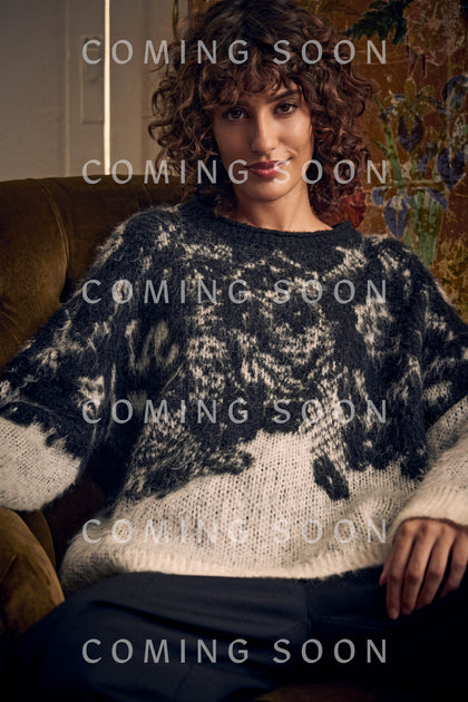 A woman wears a monochrome Floral Jacquard Knit Top, a long-sleeved sweater featuring an abstract floral pattern.