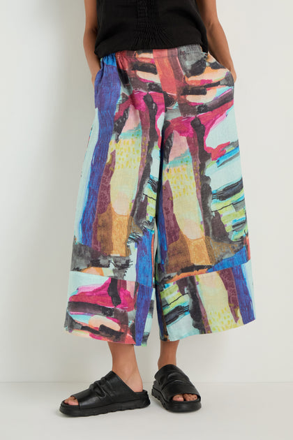 Model wears Abstract Print Wide Leg Trousers with a black top and black open-toe sandals, standing against a plain white background.