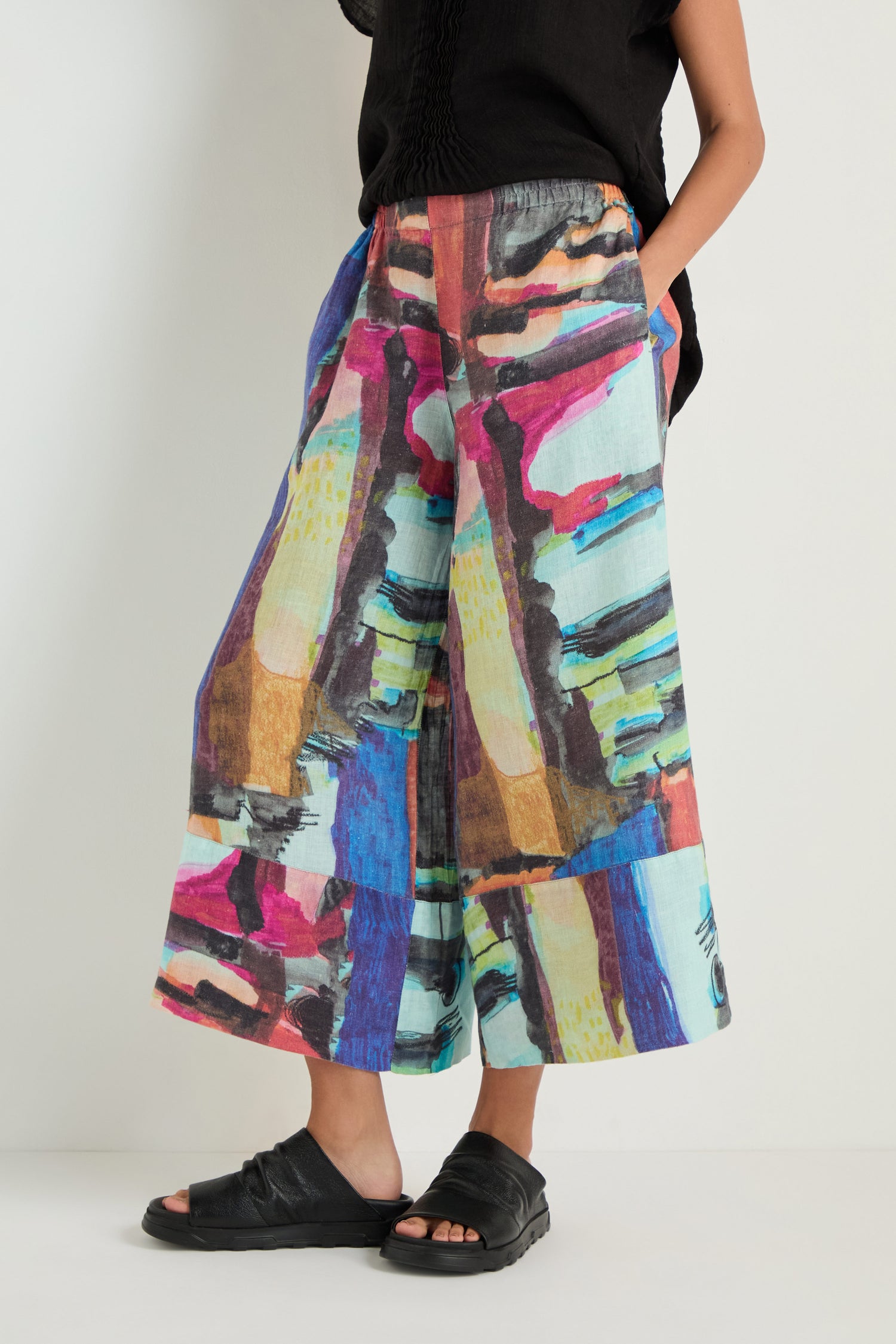 Model wears Abstract Print Wide Leg Trousers with a black top and black slide sandals, standing against a neutral background.