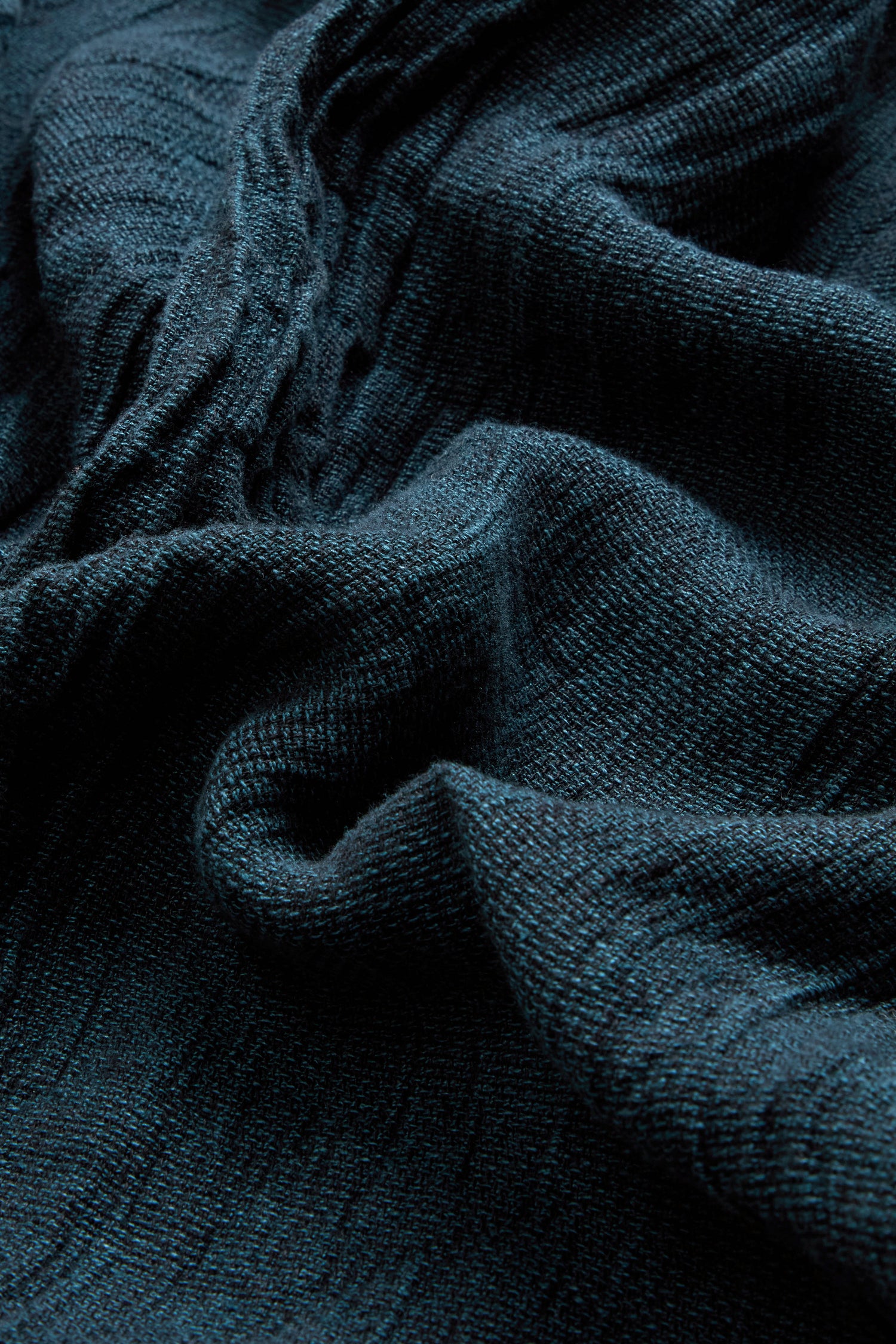 Close-up of textured turquoise linen fabric with visible folds and creases, highlighting its woven pattern and slightly rough, breathable surface. This natural material is ideal for crafting garments like the Textured Linen Turquoise Bubble Trousers.