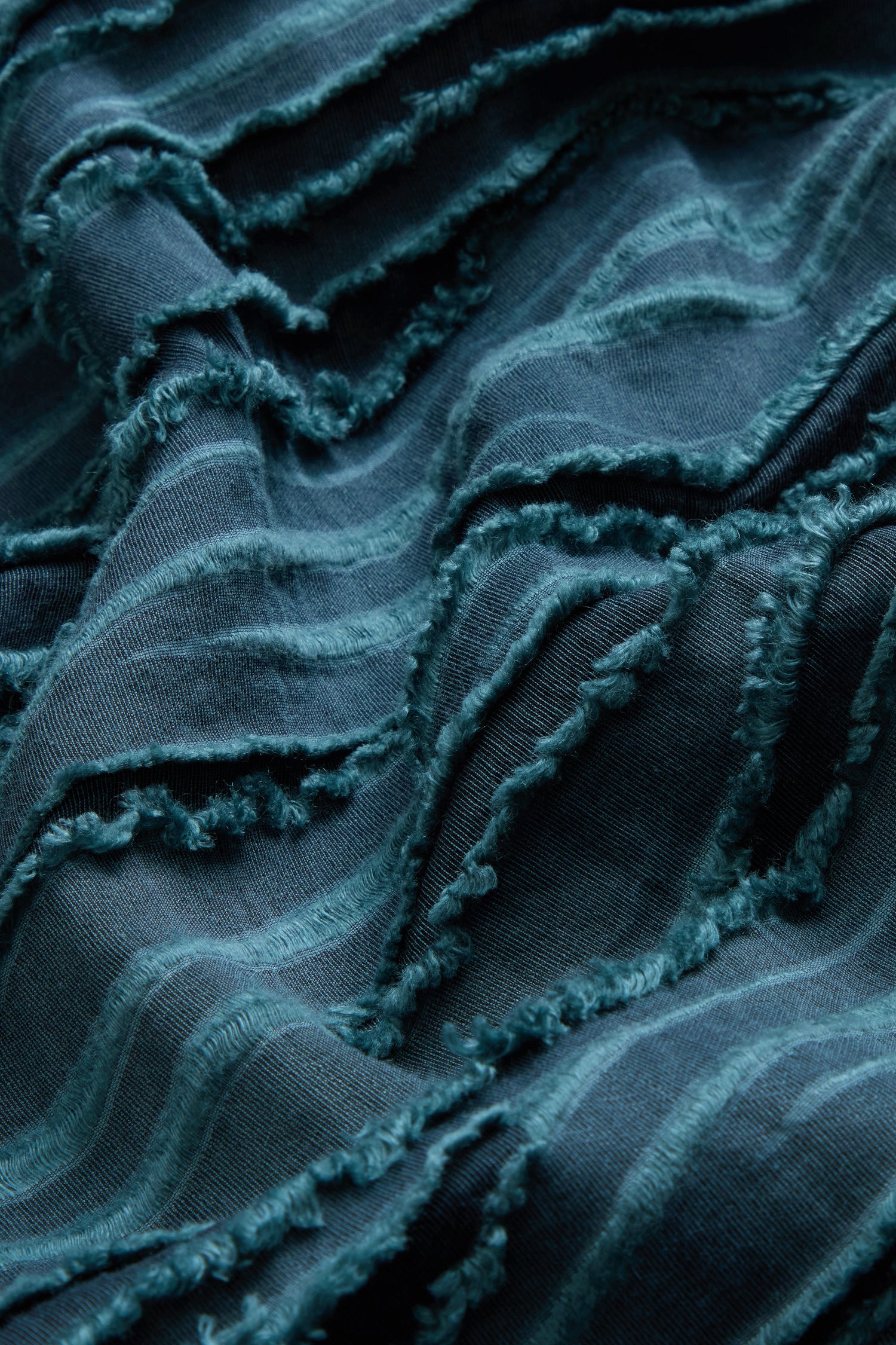 Deep turquoise fabric with horizontal raised textured stripes and frayed edges creates a wavy, layered pattern across the surface—perfectly embodied by the Deep Turquoise Textured Stripe Flared Shirt, which offers both visual depth and tactile appeal.