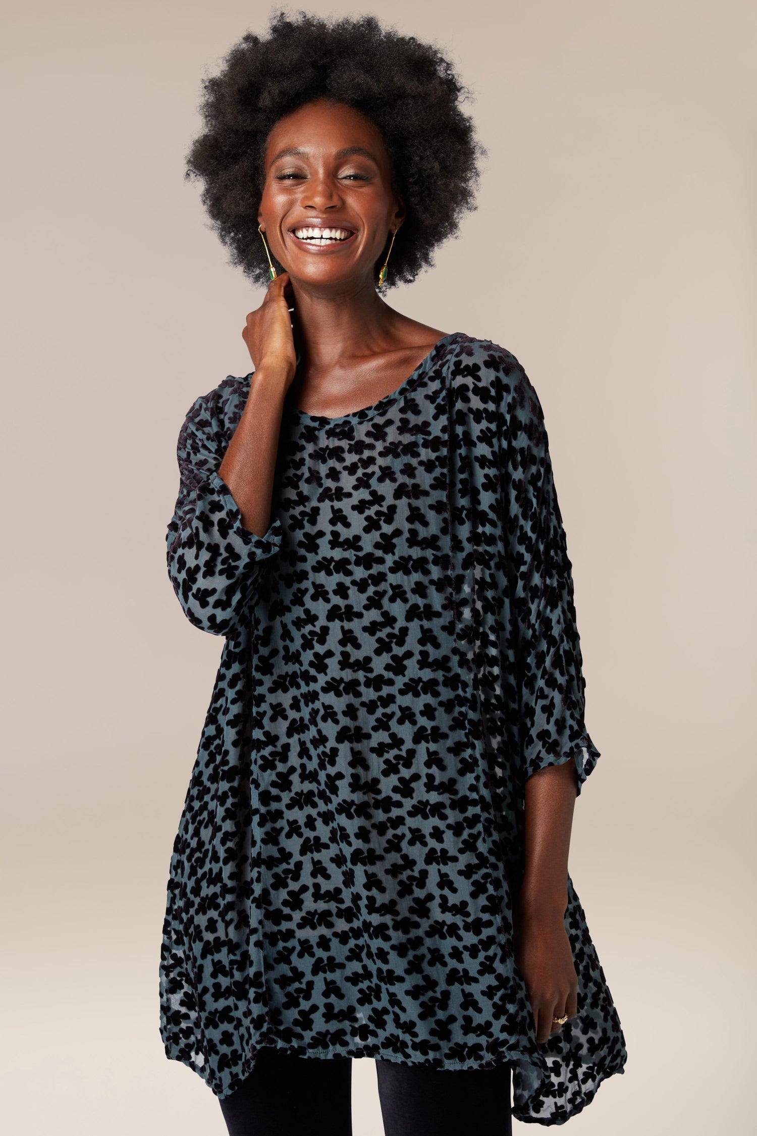 A woman wearing a Devore Tunic in black and leggings.