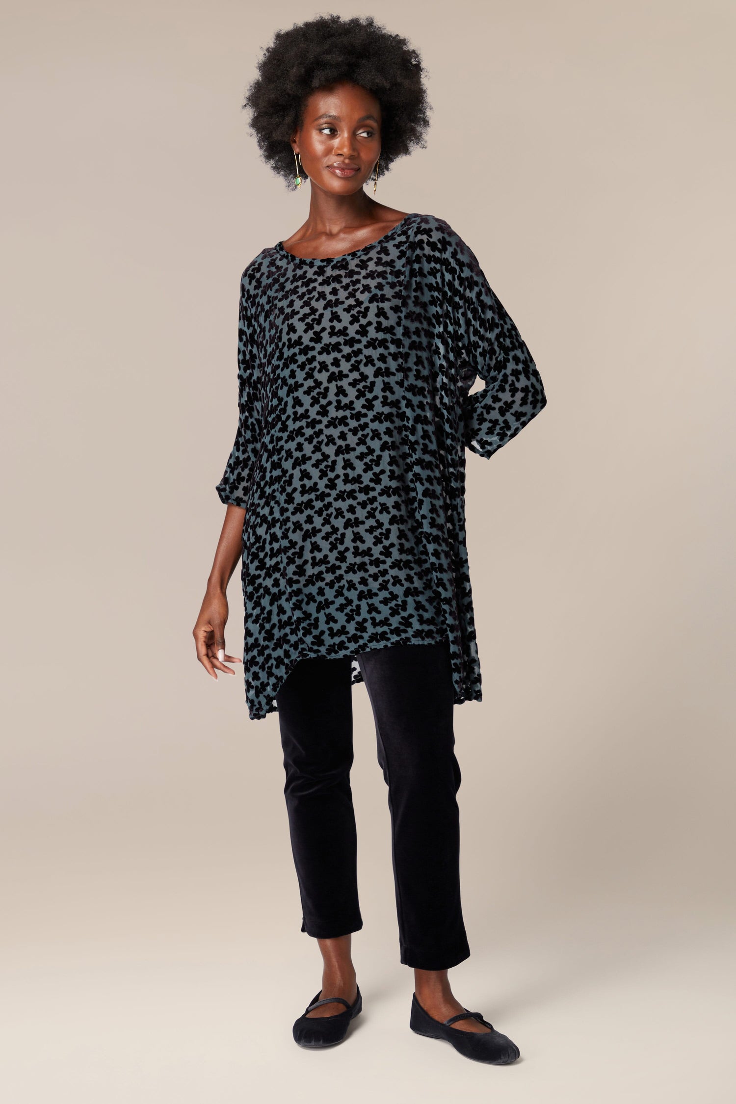 A woman donning a stylish Devore tunic paired with sleek black pants.