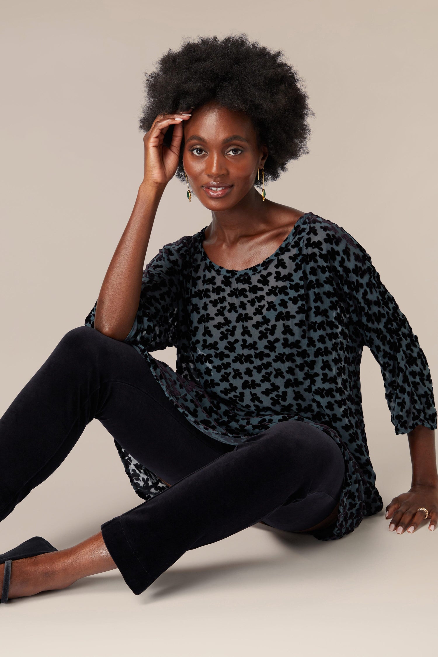 A black woman sitting on the floor wearing a Grizas burned-out velvet Devore Tunic.