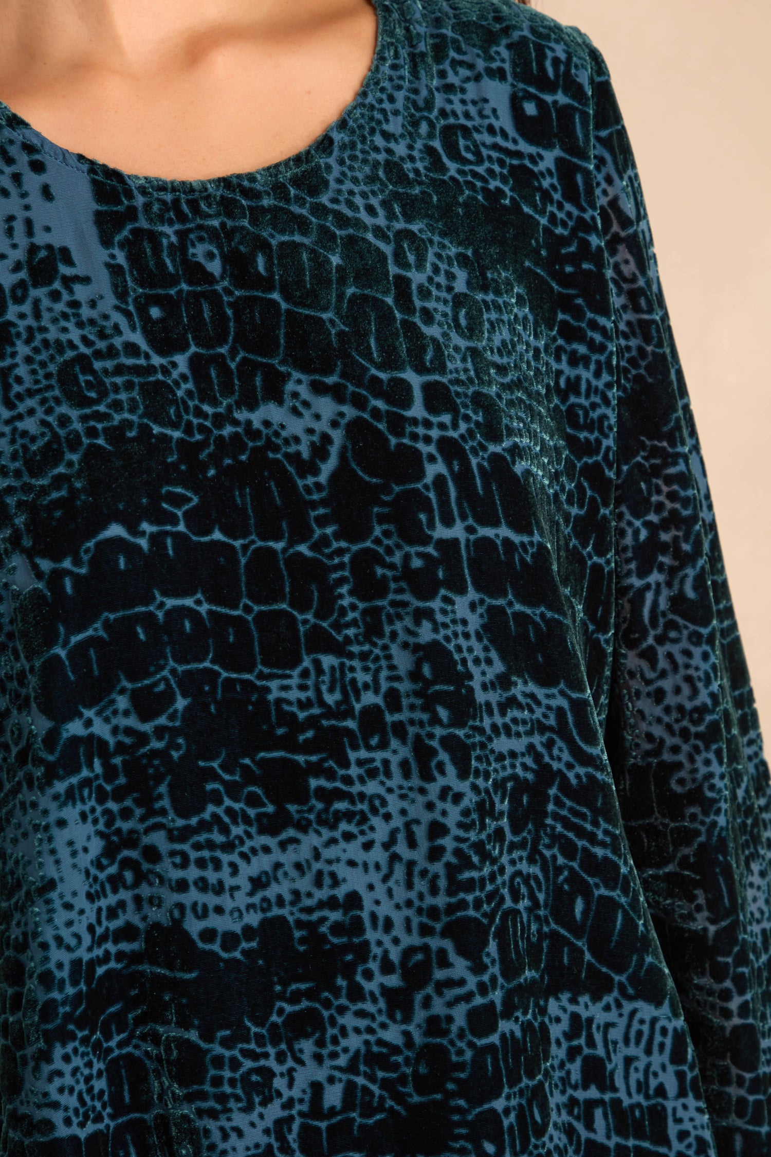 Close-up of a person in the Deep Turquoise Leopard Devore Layered, showing only the shoulder, upper chest, and part of the sleeve with its bold animal print.
