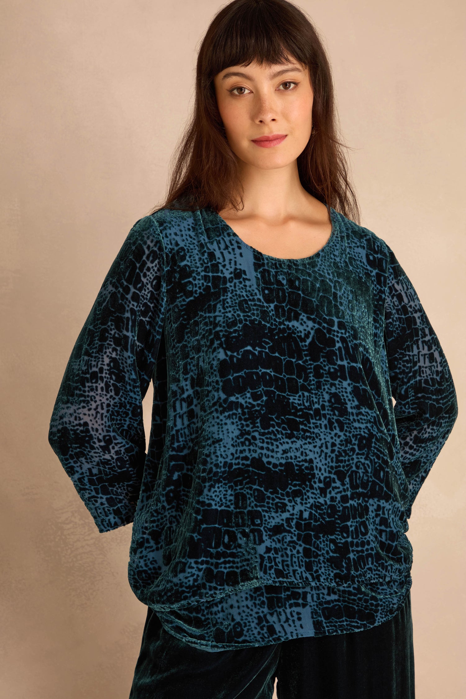 Woman wearing the Deep Turquoise Leopard Devore Layered top in dark teal and black, standing in front of a plain beige background.