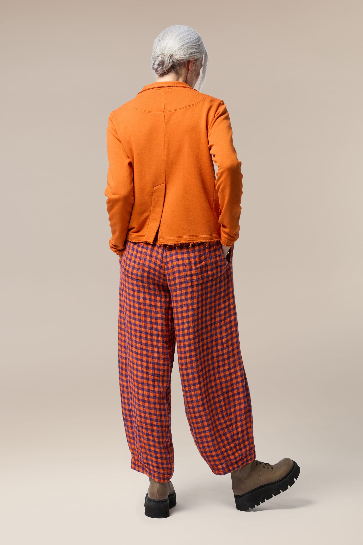 The back view of a woman wearing orange and blue checkered trousers with a Collar Jacket for her summer wardrobe.