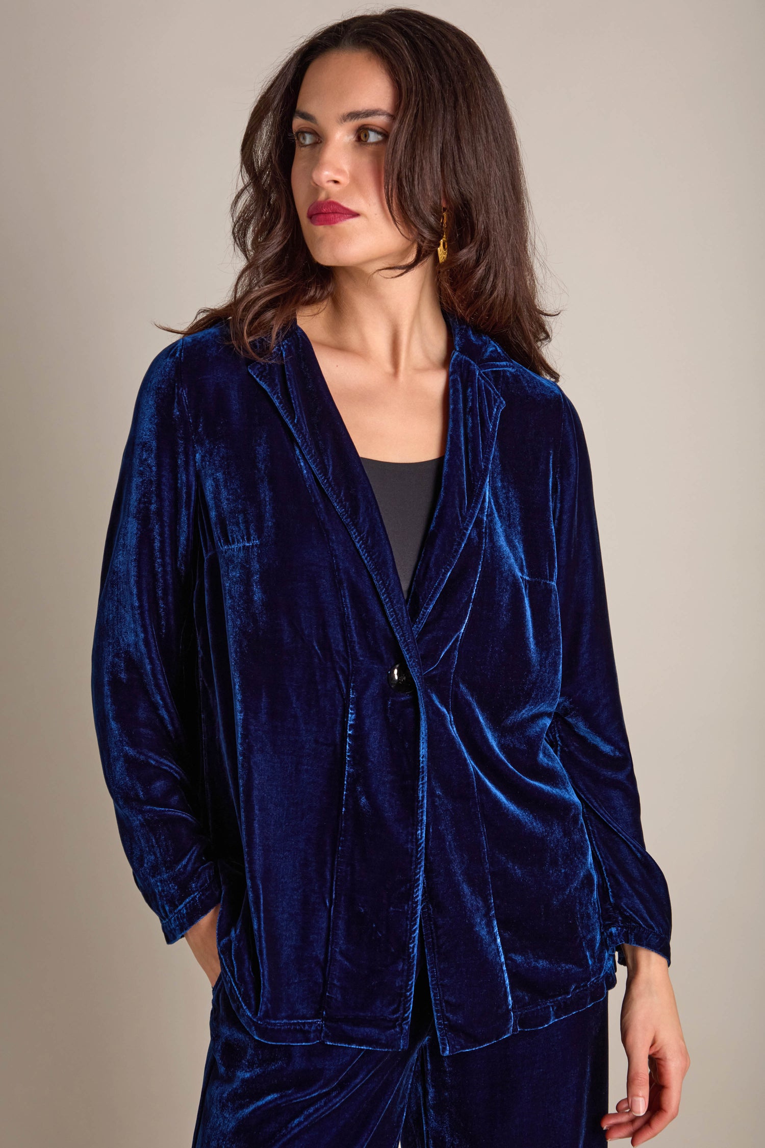 A woman wearing a Boxy Silk Velvet Jacket stands with her hands in her pockets, looking to the side.