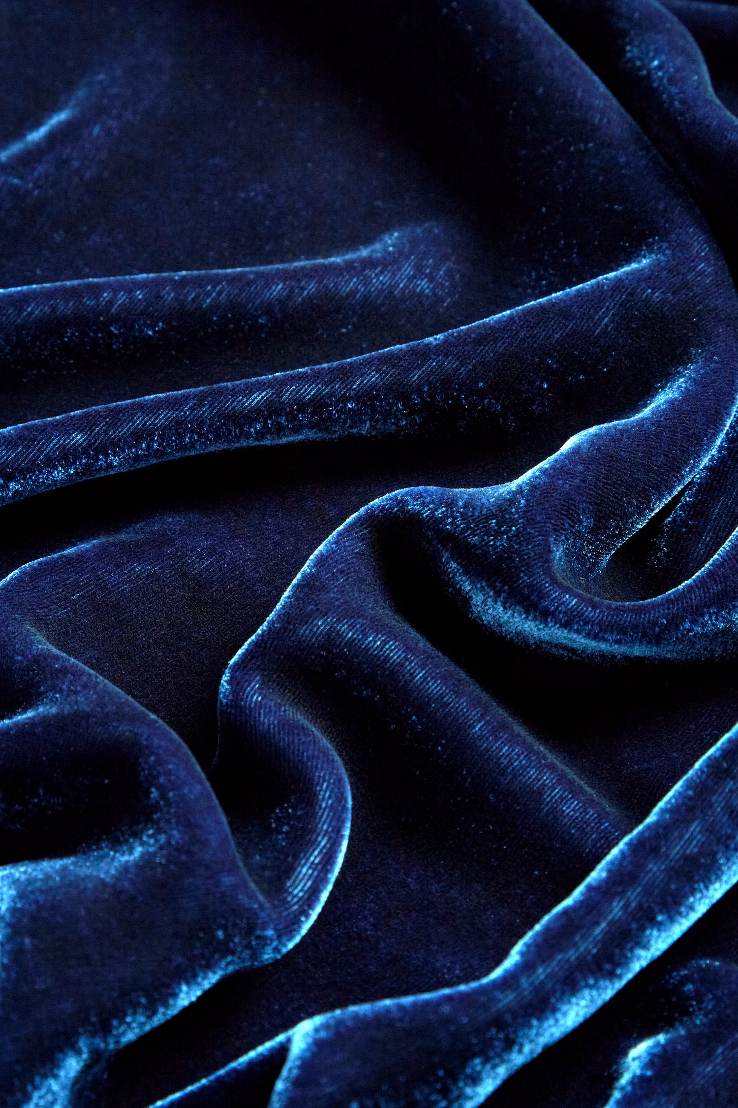 Close-up of deep blue velvet fabric with folds and a lustrous sheen, similar to the Boxy Silk Velvet Jacket.