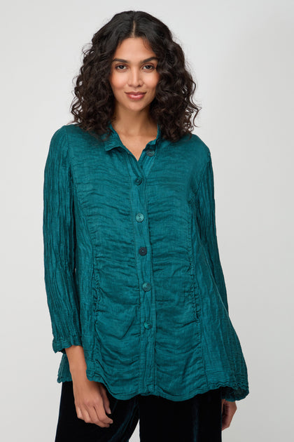 Woman wearing the Panel Front Silk Linen Jacket in teal, featuring long sleeves, a collar, and textured fabric, standing against a plain light background.