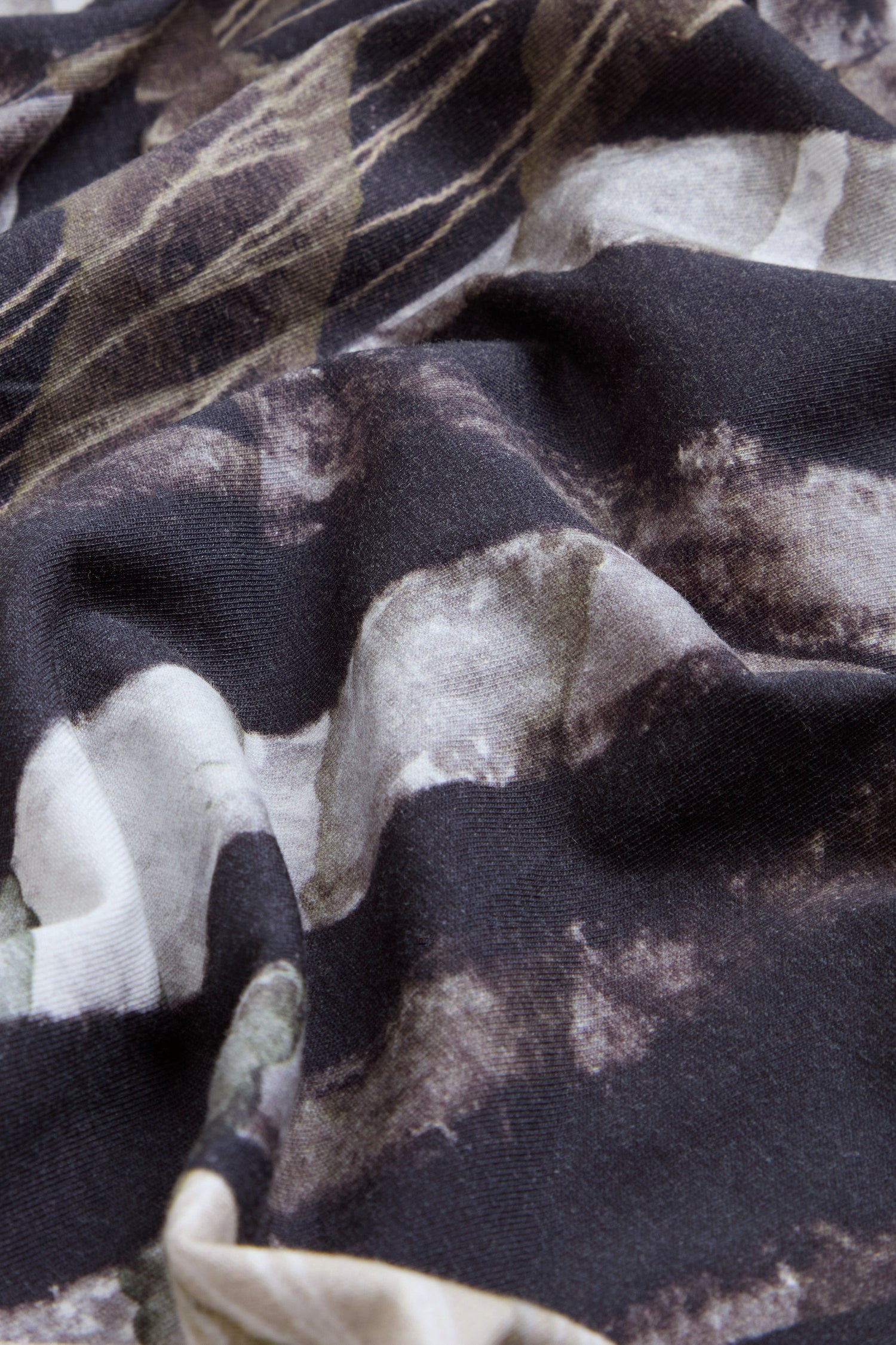 Close-up of the Monochrome Patchwork Jersey Dress, showcasing its crumpled stretch cotton jersey fabric with a dark abstract pattern in shades of black, brown, gray, and beige.