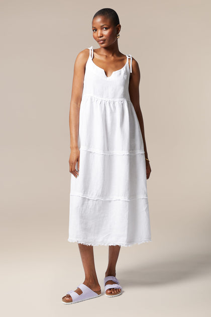 A woman wearing a Linen Tiered Dress with adjustable shoulder ties.