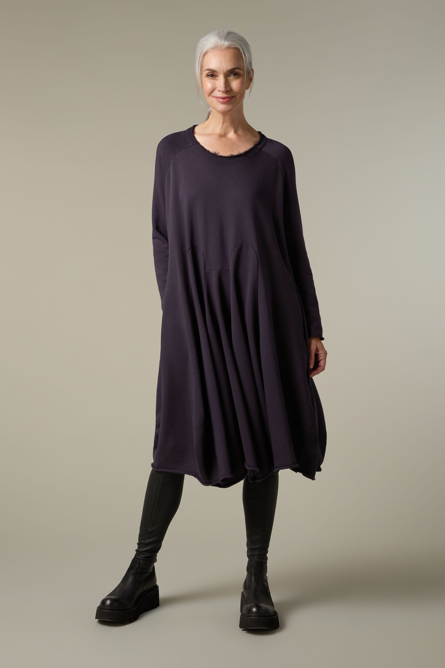 A woman wearing a Godet Jersey Dress and black leggings.