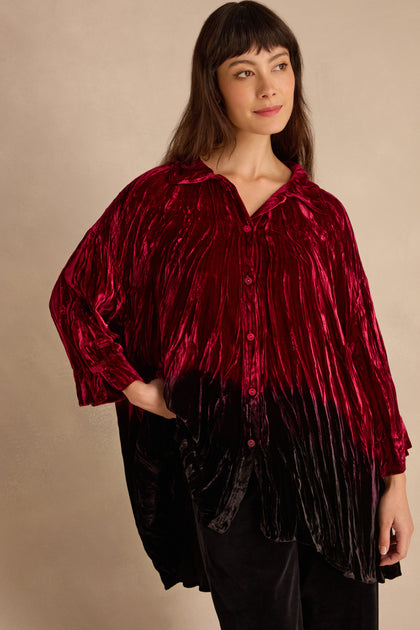 Woman wearing the Ruby Silk Velvet Ombre Shirt—loose, shiny red and black crushed velvet with long sleeves—standing against a neutral background.