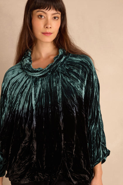 A person with long brown hair wears the Turquoise Silk Velvet Ombre Cowl Neck Top, standing in front of a plain beige background.