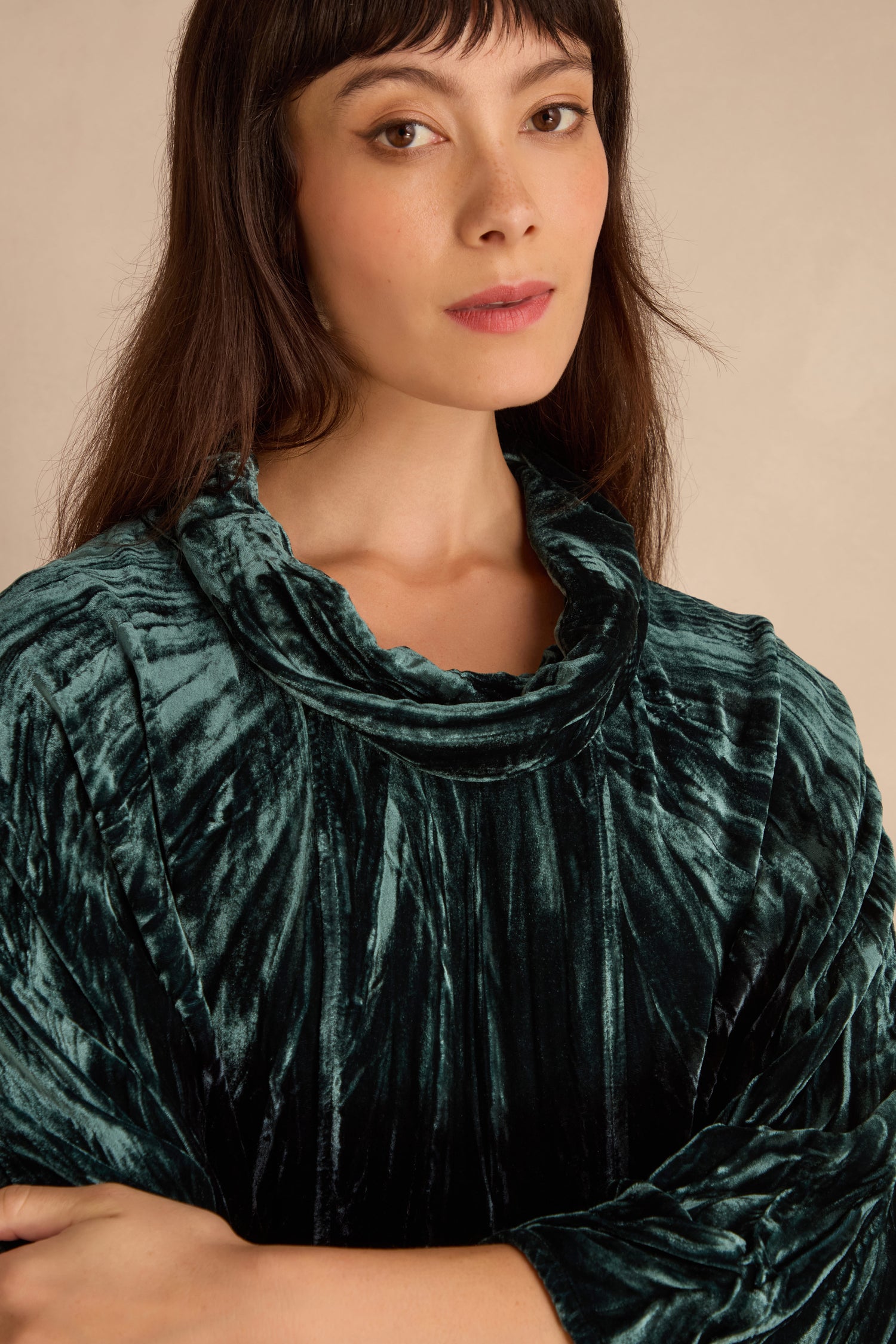 Woman with long brown hair and bangs wears the Turquoise Silk Velvet Ombre Cowl Neck Top, standing against a neutral background.