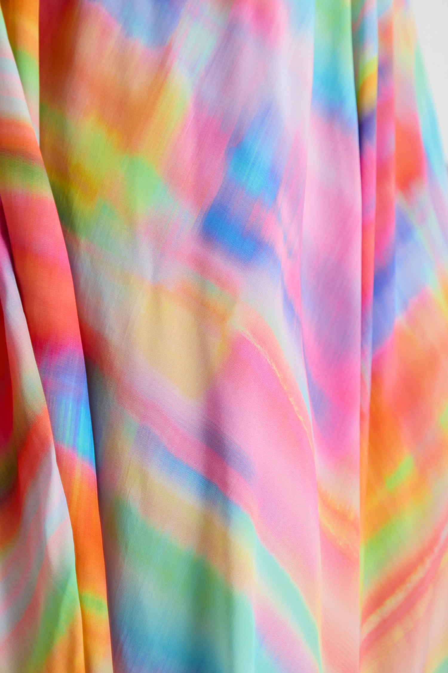 Close-up of the Painted Horizon Bubble Dress, featuring soft, abstract tie-dye patterns in pink, blue, green, orange, and yellow—evoking a painted horizon across its flowing silhouette.