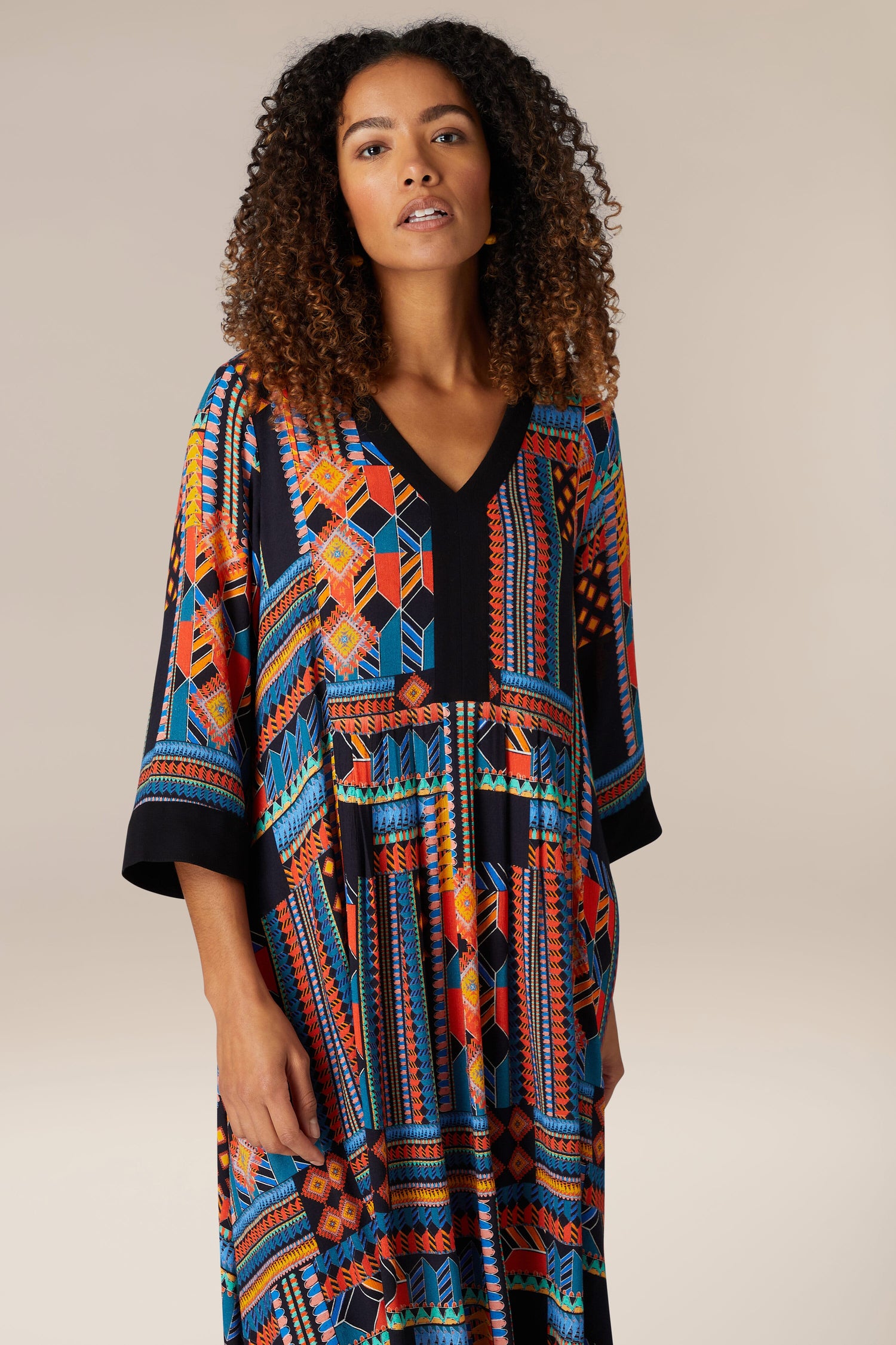 A woman exuding bohemian elegance in a vibrant patterned Bold Graphic Printed Dress made of viscose.