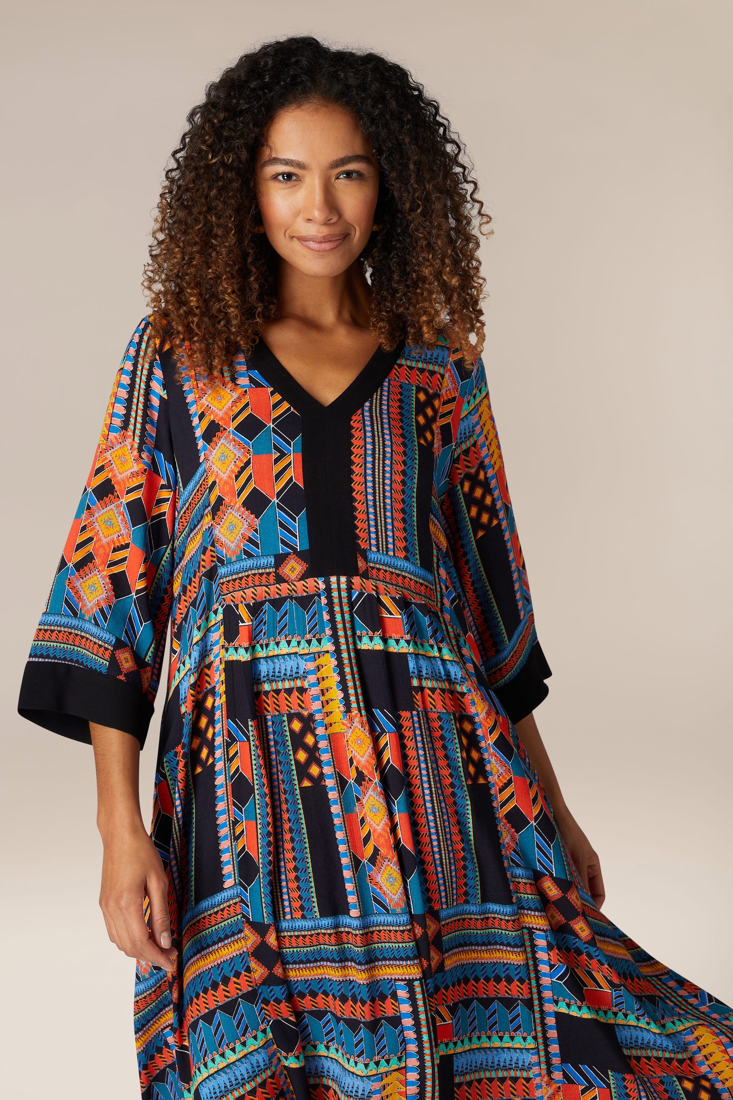 A woman wearing a Bold Graphic Printed Dress with a v-neck, showcasing bohemian elegance.