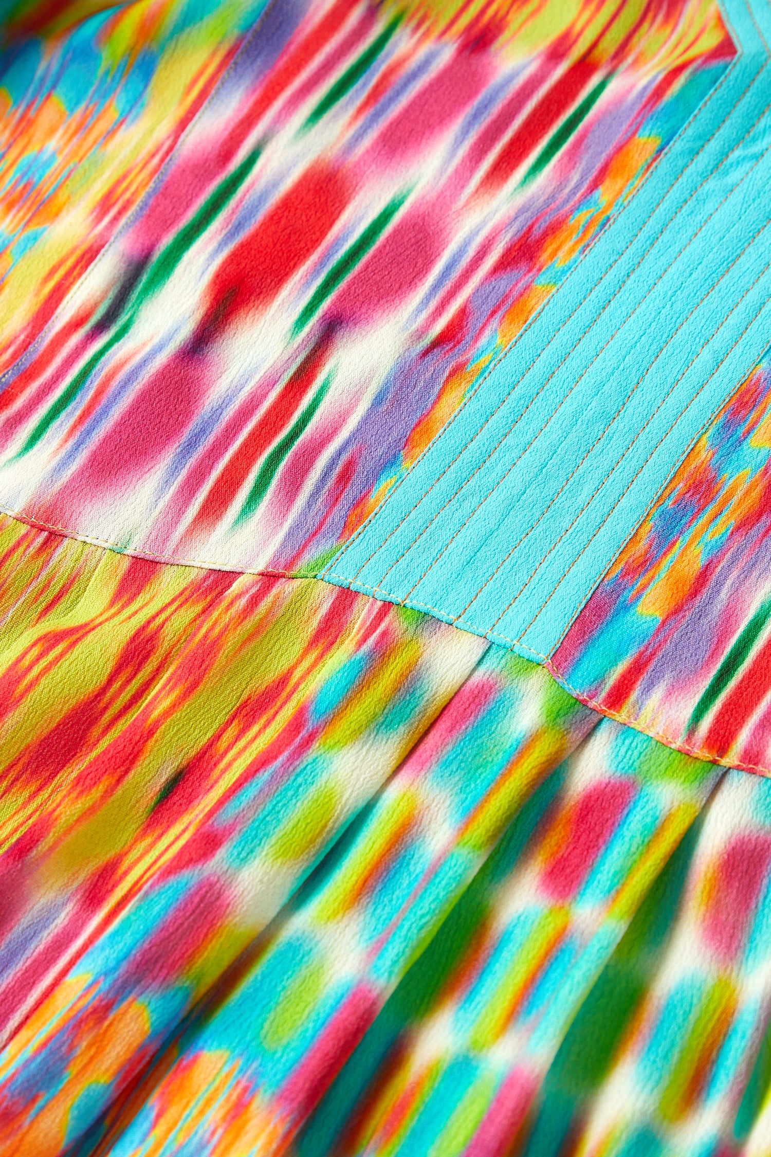 A close up of a embroidered Kaleidoscope Ikat Flare Dress neckline on a colorful fabric.